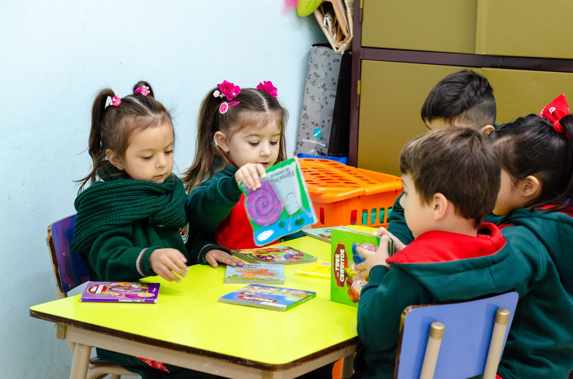 Niños y niñas del jardín del Instituto Leloir mirando cuentos en una mesa del aula